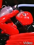 Mistress putting on red latex overall